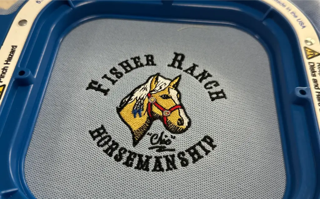 Fisher Ranch horse head embroidery design in a blue hoop, showcasing quality craftsmanship for business branding and promotional products.