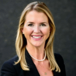 Professional headshot of Janel Carothers, Chief Sales Officer of Elite Shirt Company, smiling in business attire against a dark background.